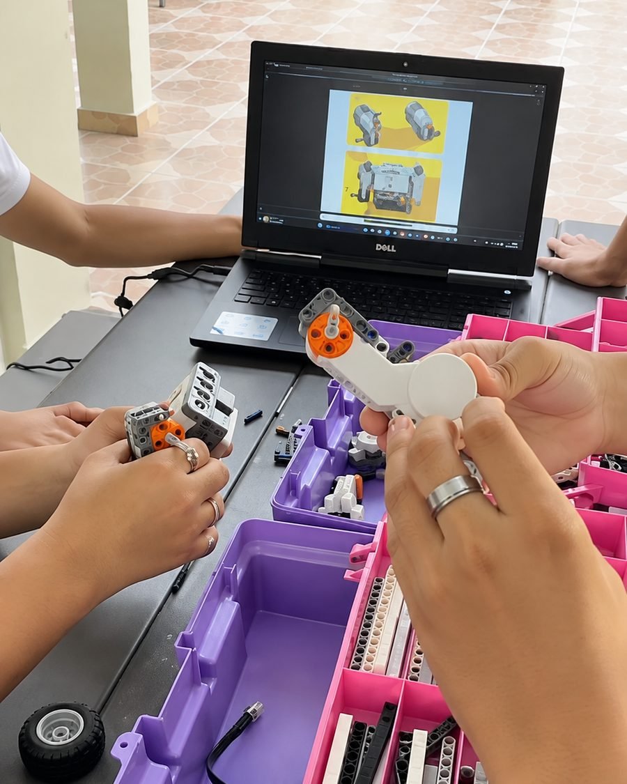 Estudiantes armando un robot siguiendo la guía en la laptop